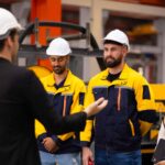 Finance broker meeting a manufacturing team on the factory floor to discuss restructuring the business's debt.